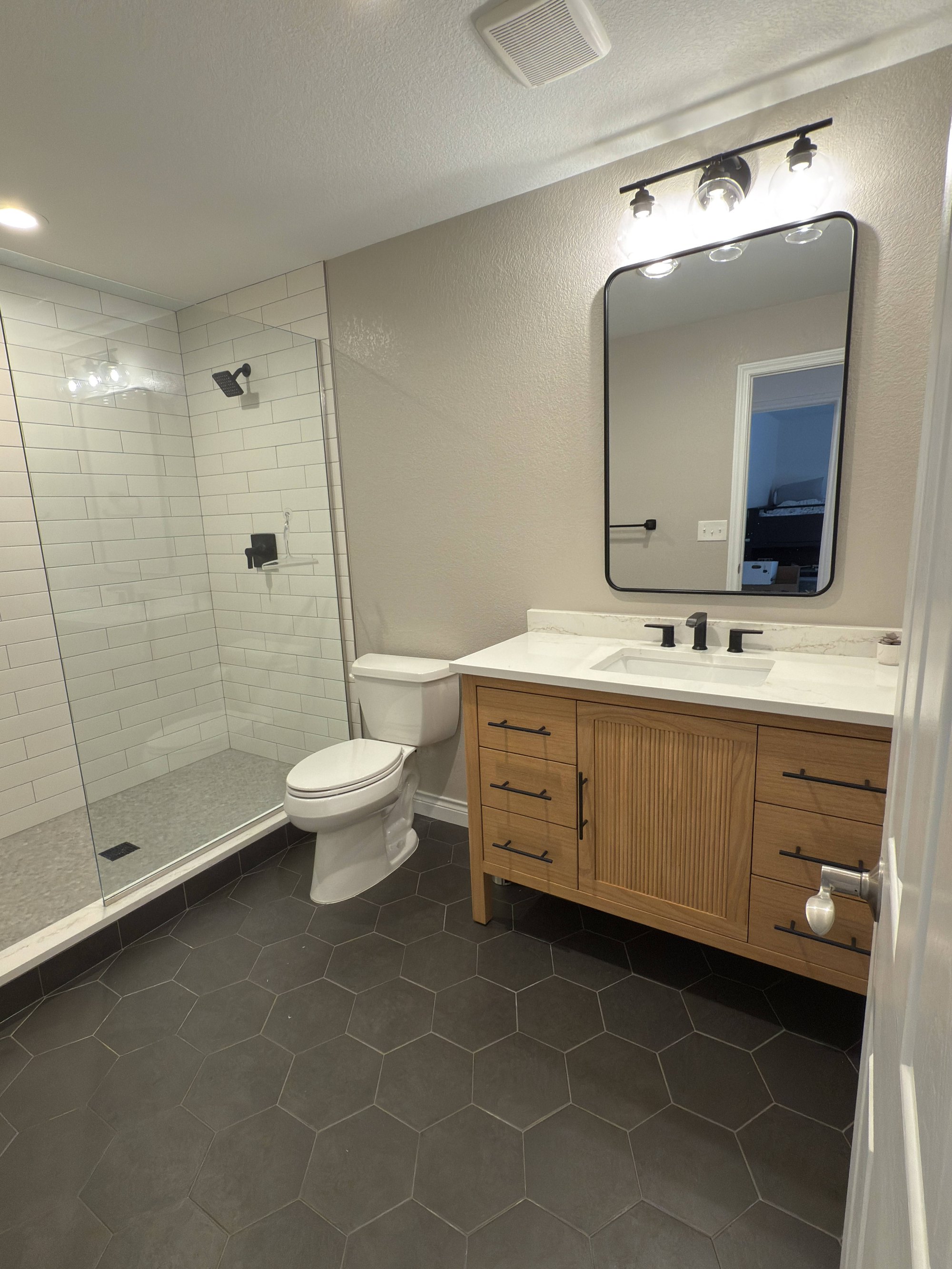 after basement remodel luxury bathroom with custom vanity and tiled shower in littleton