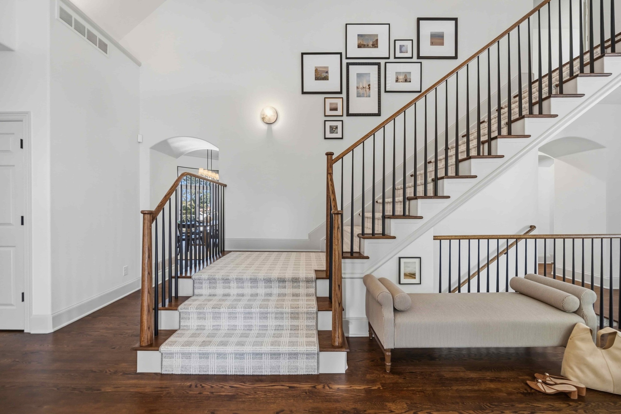 Elegant remodeled staircase with patterned carpet runner, wood handrails, black iron balusters, and gallery wall in a Greenwood Village home Elegant remodeled staircase with patterned carpet runner, wood handrails, black iron balusters, and gallery wall in a Greenwood Village home
