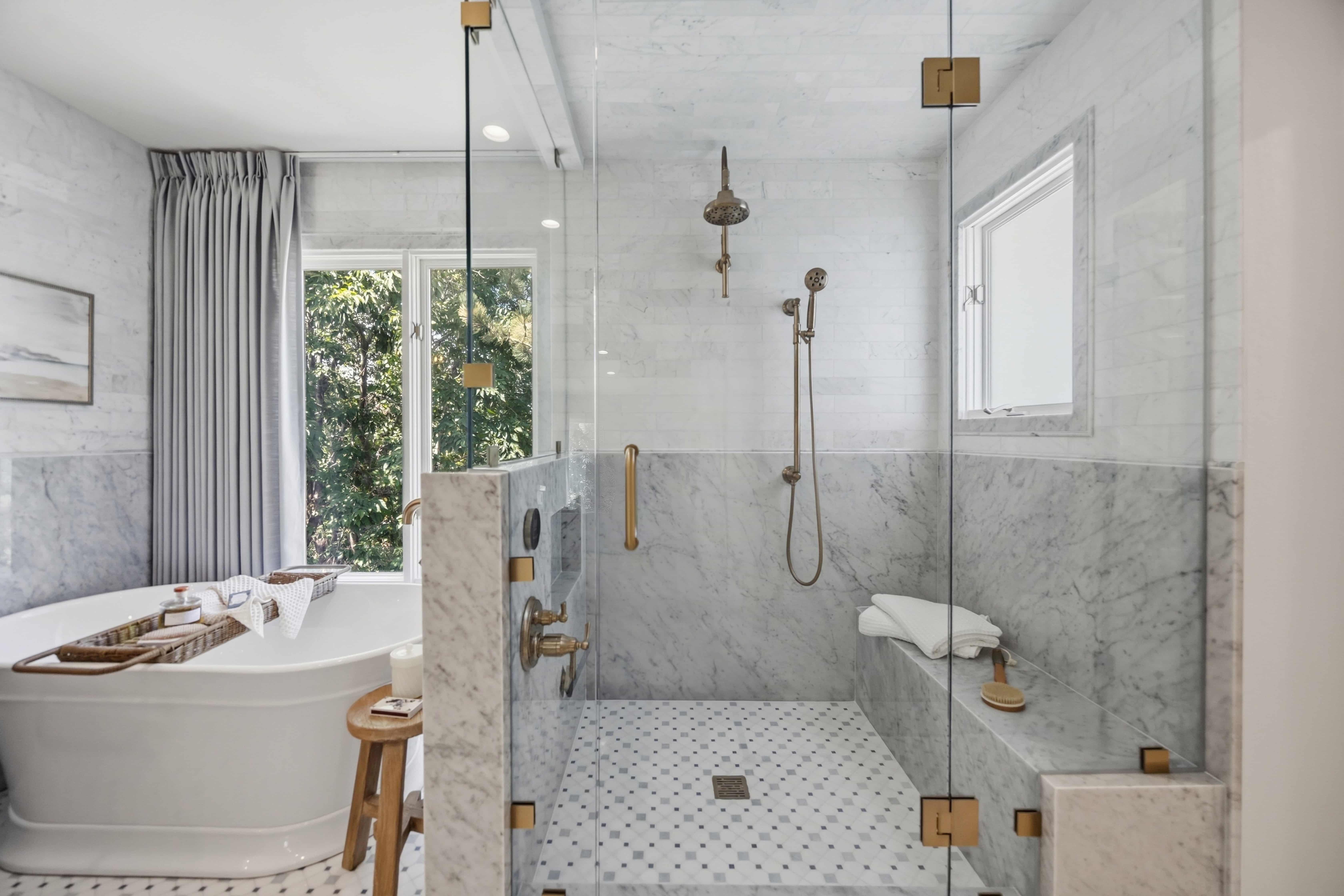 Luxury primary bathroom remodel featuring a spacious glass-enclosed walk-in shower, marble tile, brass fixtures, and freestanding soaking tub in Greenwood Village, CO