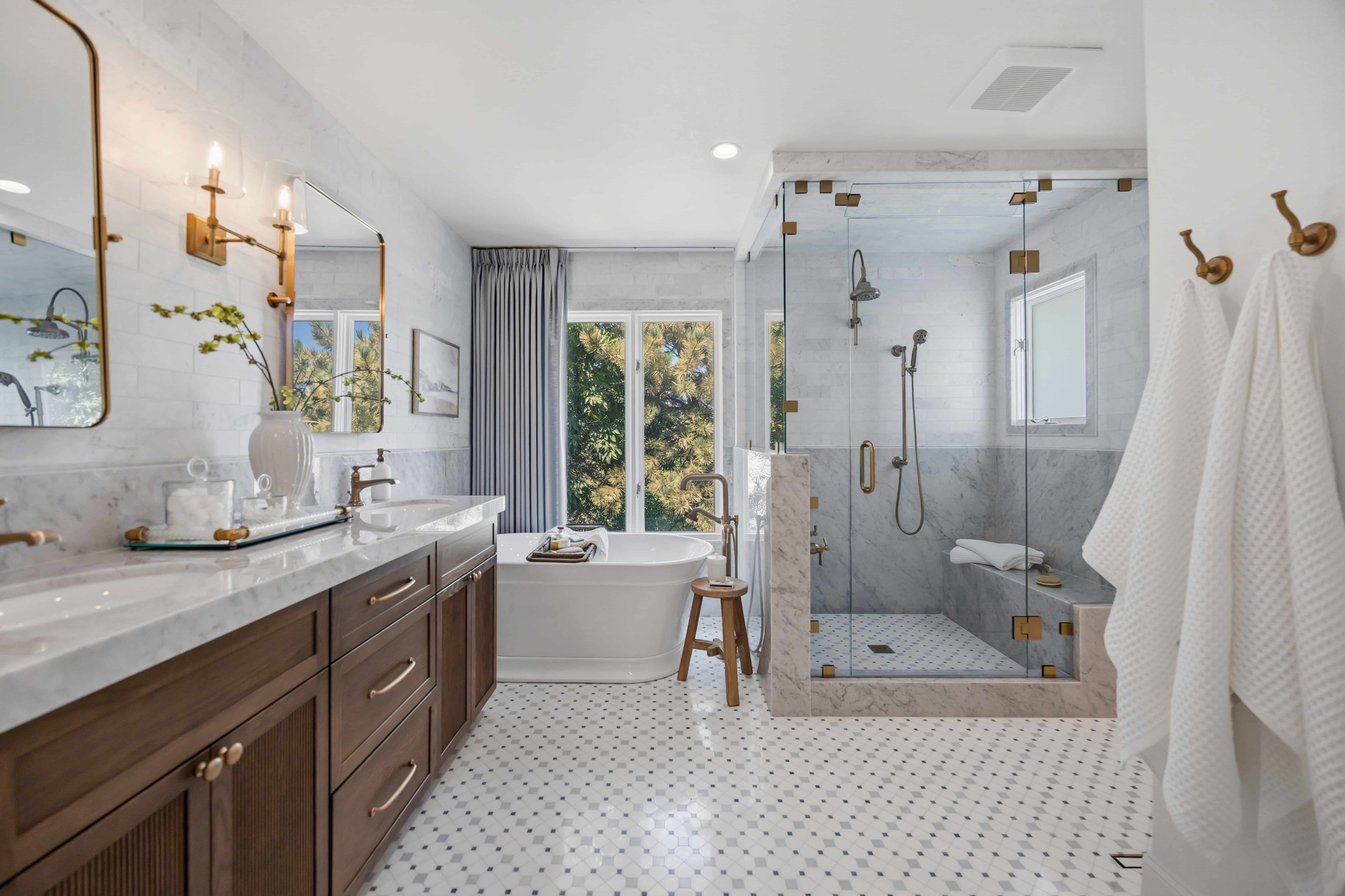 Primary bathroom remodel with double wood vanity, marble countertops, freestanding soaking tub, and glass-enclosed shower in Greenwood Village, CO