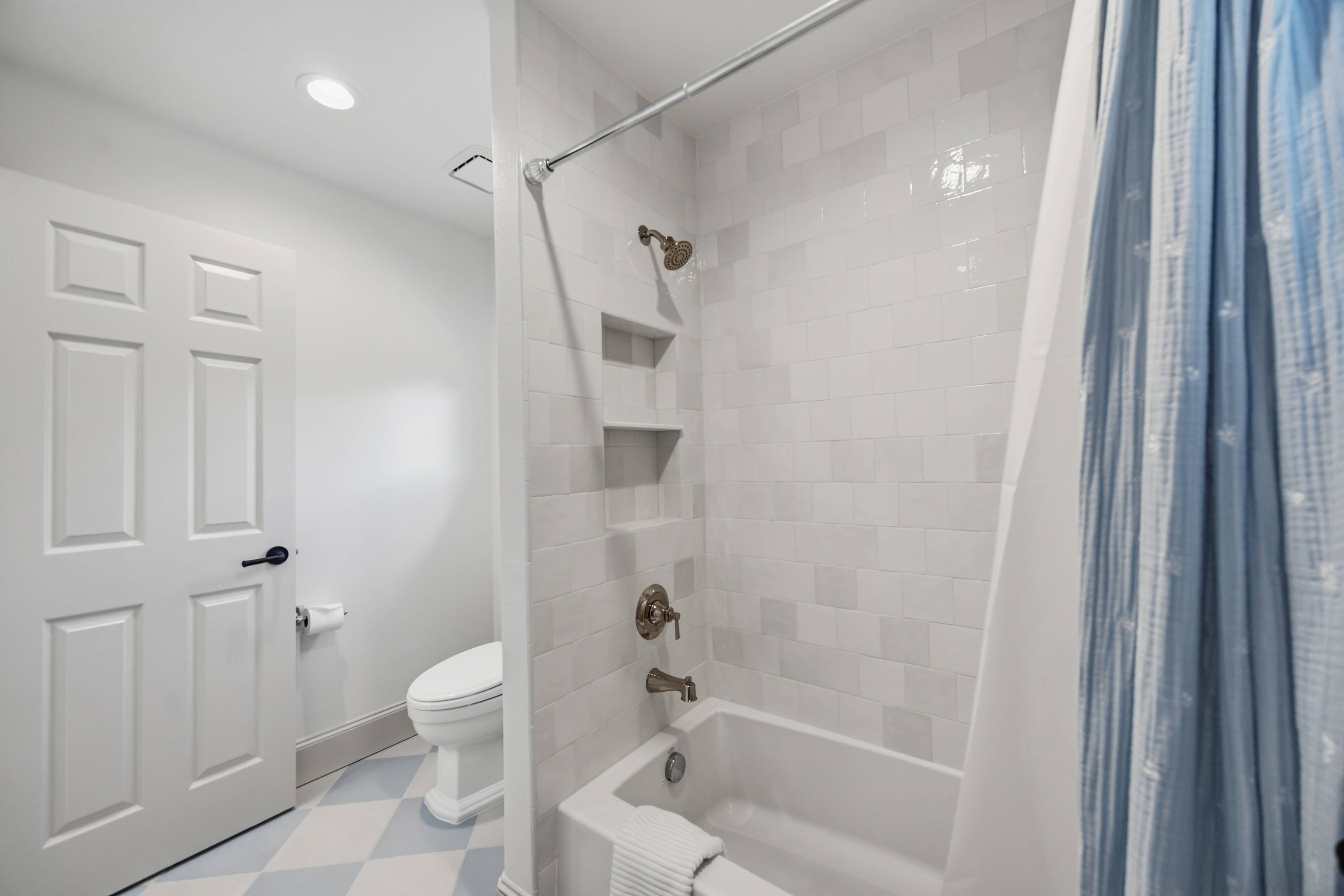 Remodeled bathroom featuring a white subway tile tub and shower surround, built-in shower niche, and blue-gray checkered flooring in Greenwood Village, CO