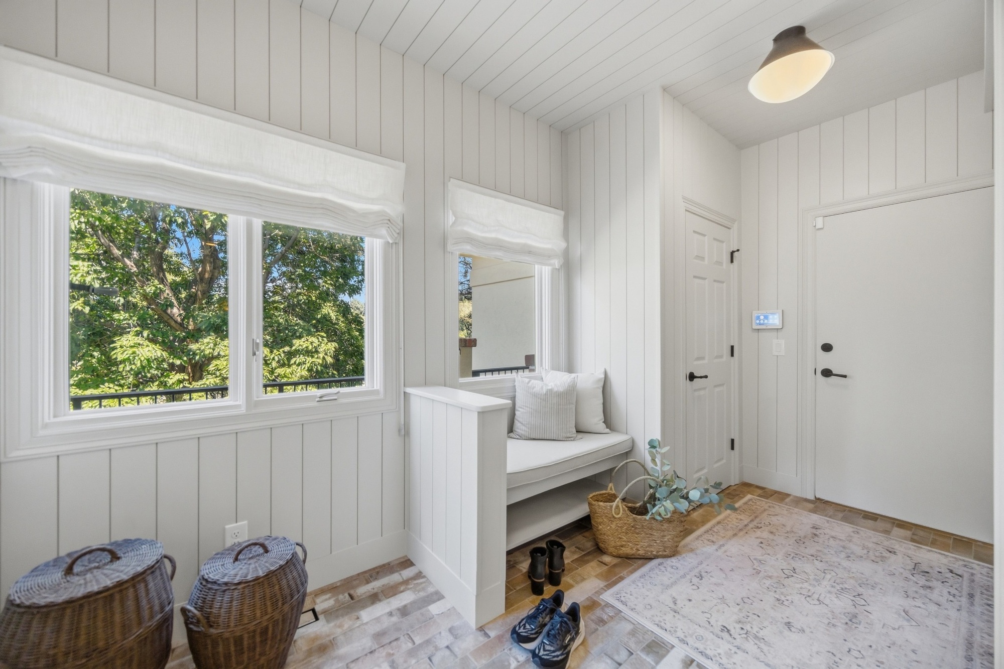 mudroom entry with white vertical paneling built in bench and brick floor in greenwood village co whole home remodel