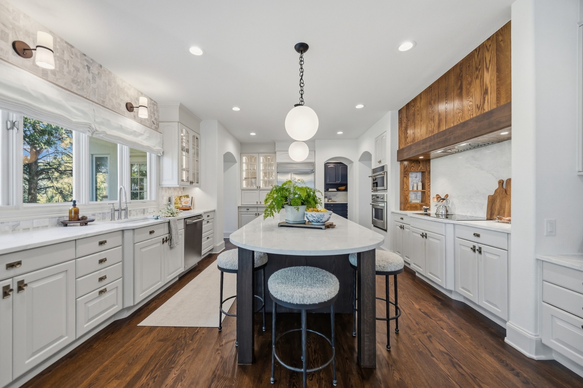 white kitchen with large island wood range hood and globe pendants in greenwood village co whole home remodel