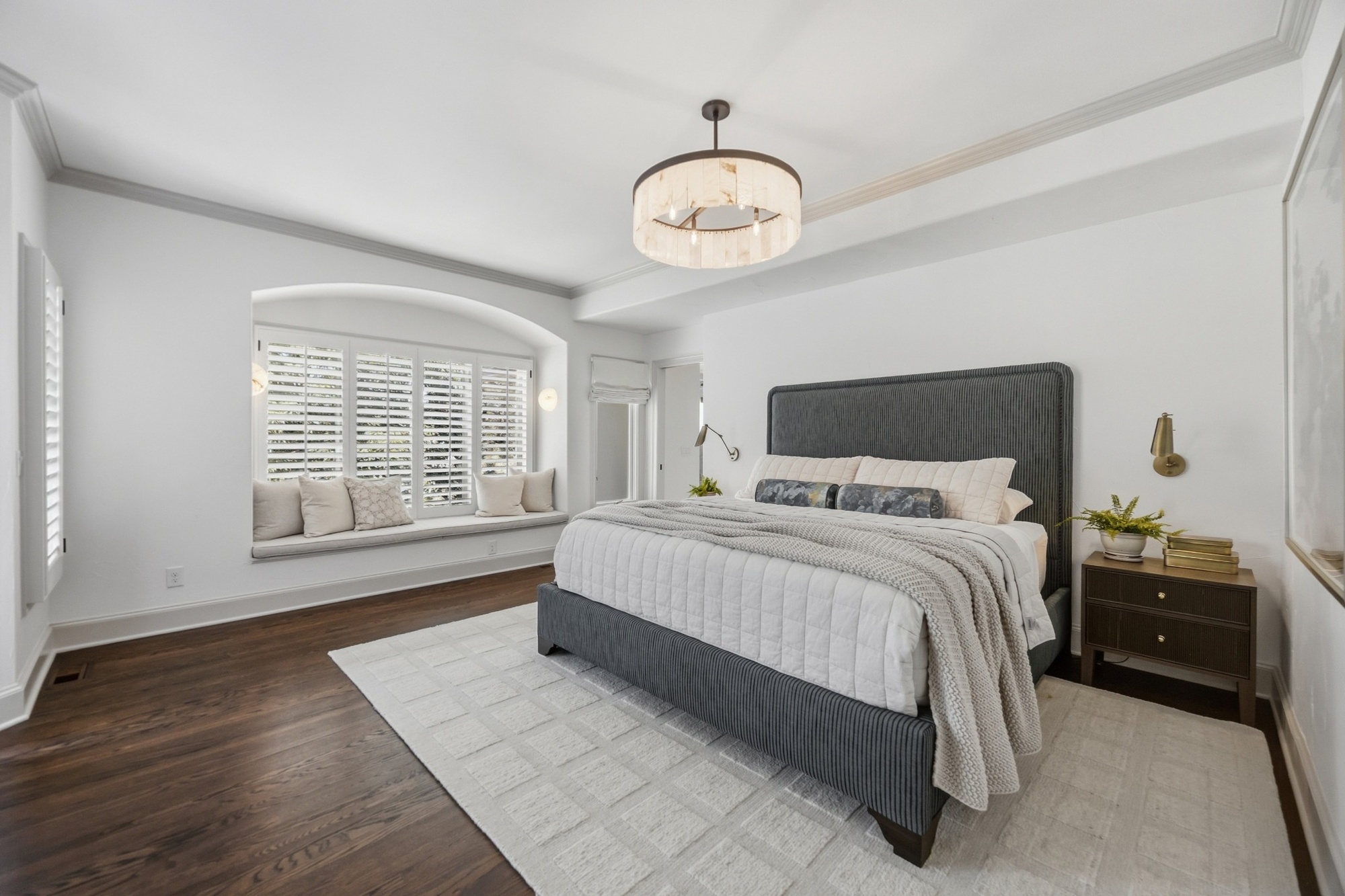 whole home remodel primary bedroom with upholstered bed hardwood floors and window seat in greenwood village co