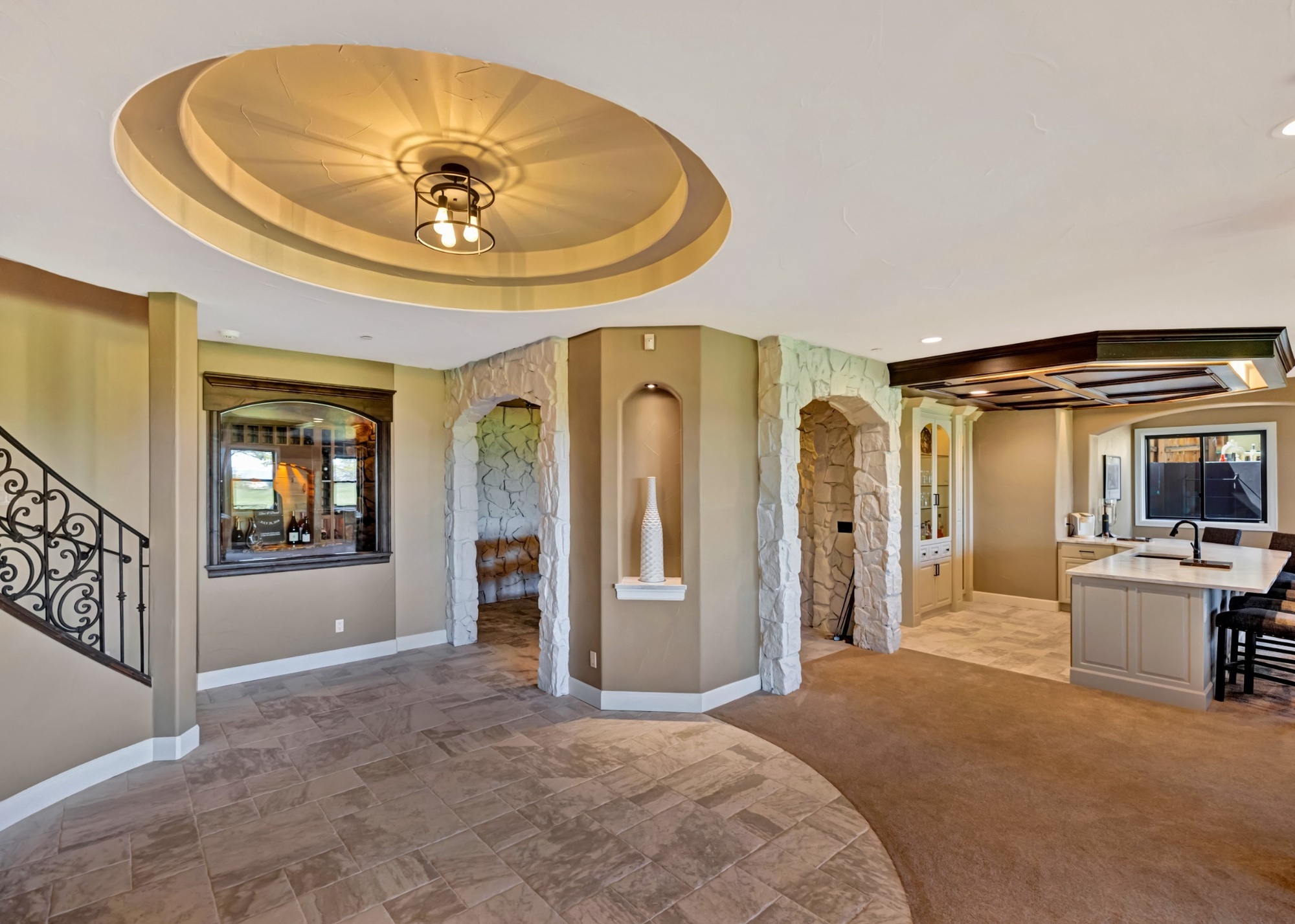 After Castle Pines whole home remodel, basement entertainment area with stone archways and custom wet bar