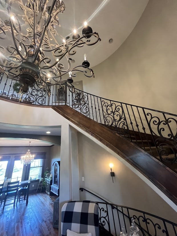 Before castle pines whole home remodel curved staircase with wrought iron railing and chandelier