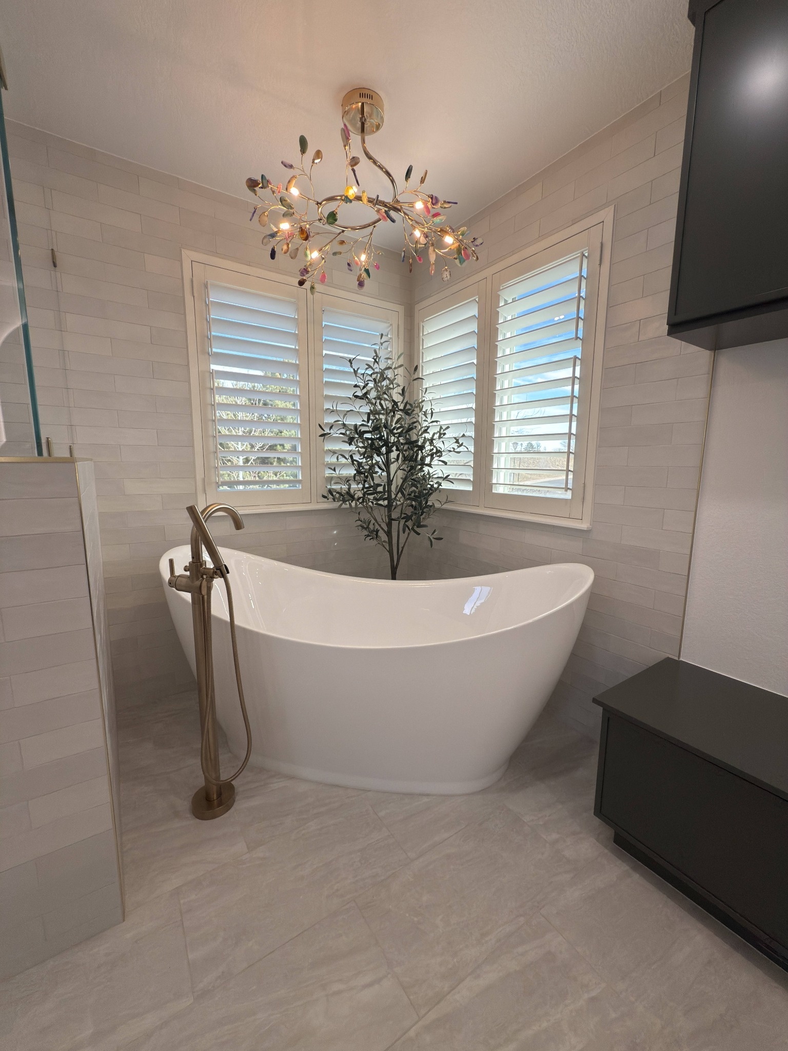 after littleton bathroom remodel freestanding tub beneath plantation shutters and decorative chandelier
