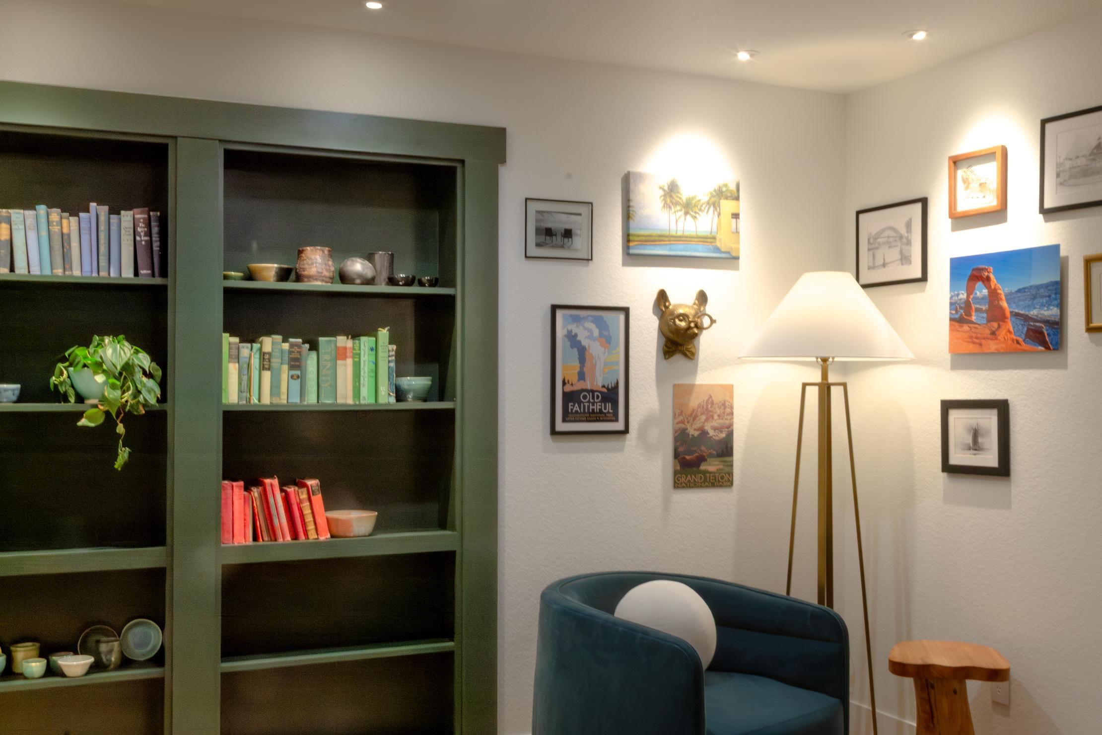 Corner view of green built-in with mid-century modern chair in basement remodel in Denver by Grimes Home Concepts